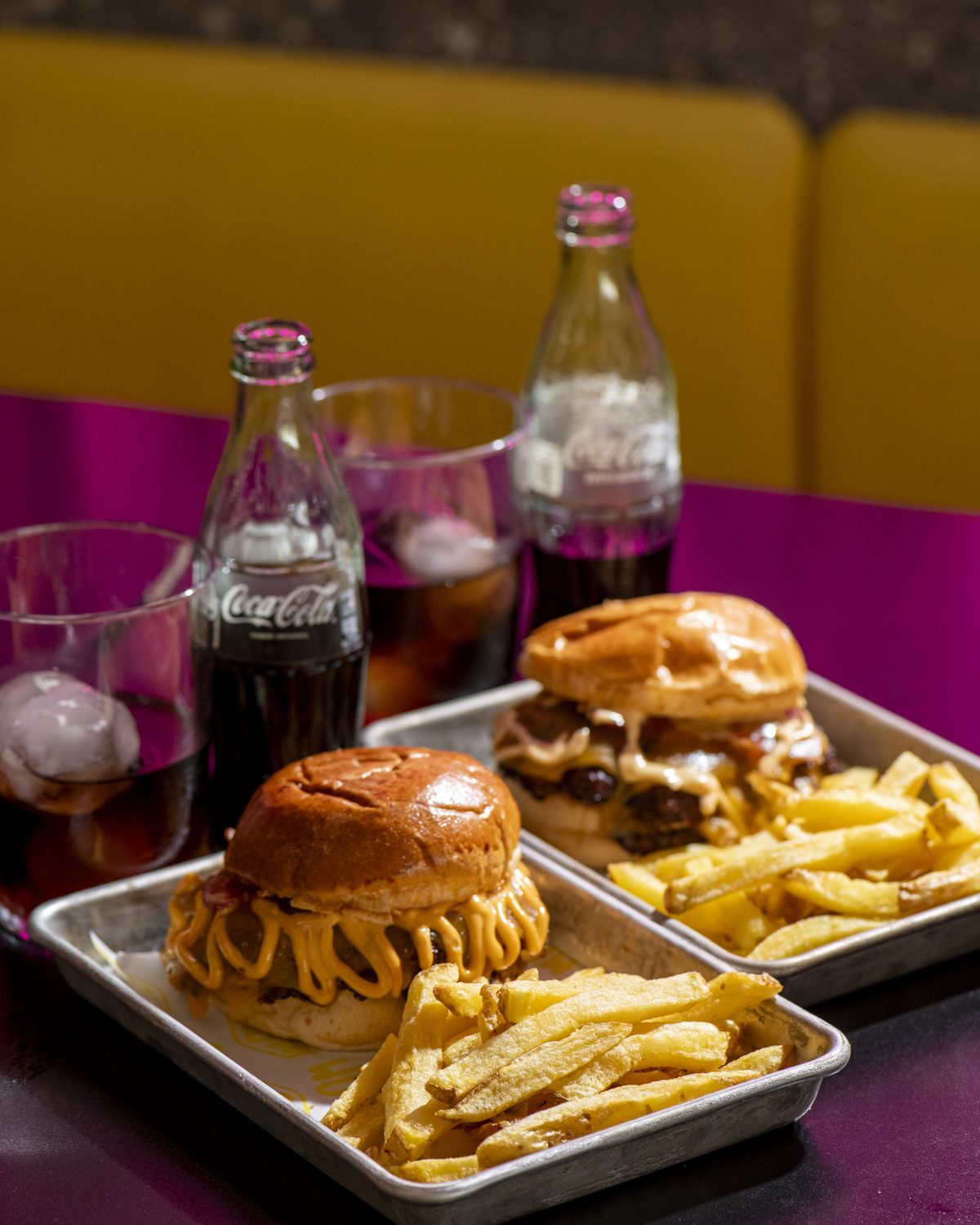 Hamburguesa con patatas y refrescos en mesa del local