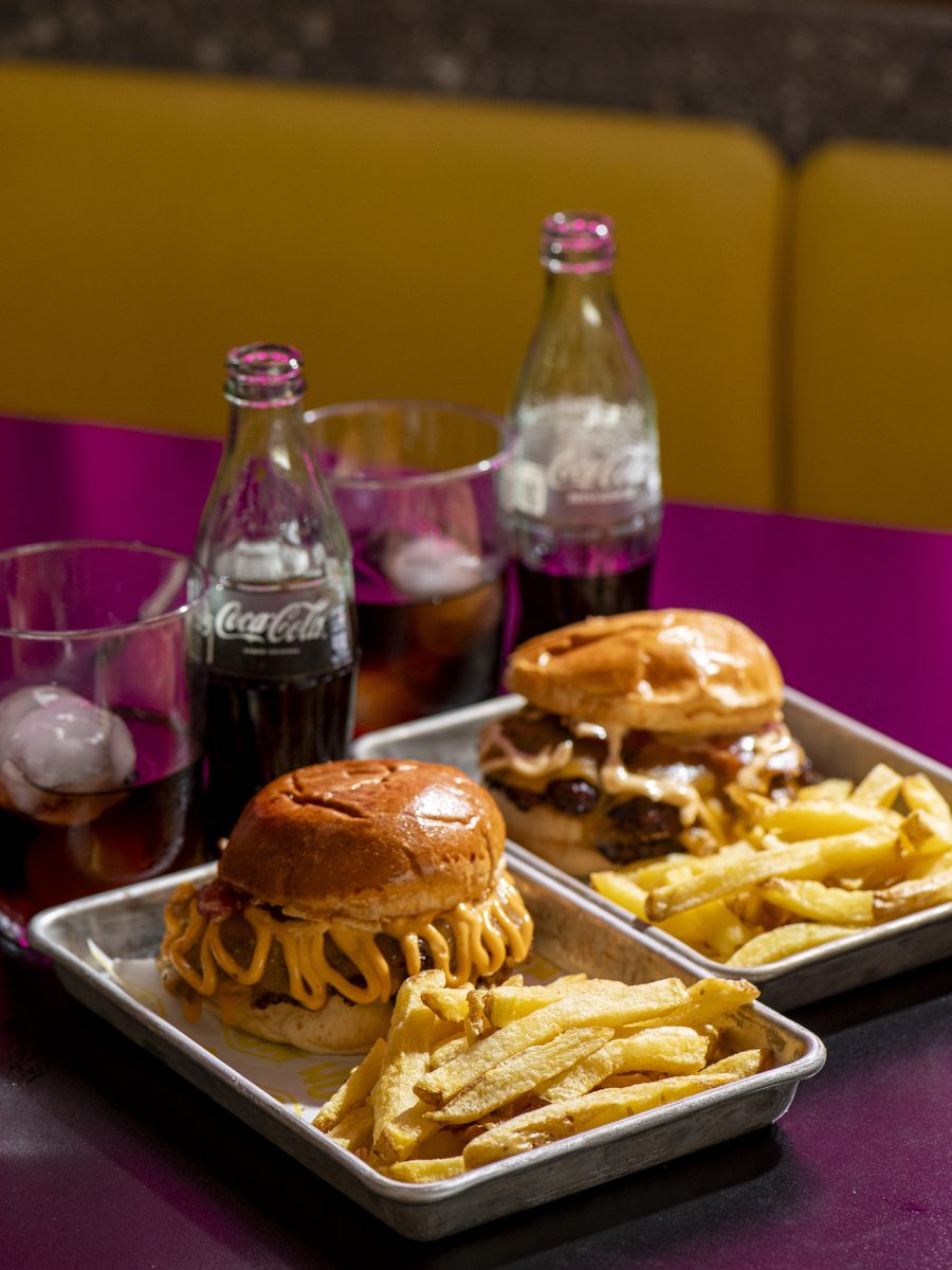 Mesa con hamburguesas WOW y refrescos en el local de Camas
